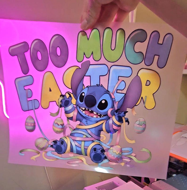 May include: A colorful graphic featuring the character Stitch from Lilo & Stitch, wrapped in pastel ribbons and surrounded by Easter eggs. The text "TOO MUCH EASTER" is displayed in large, playful letters above the character.