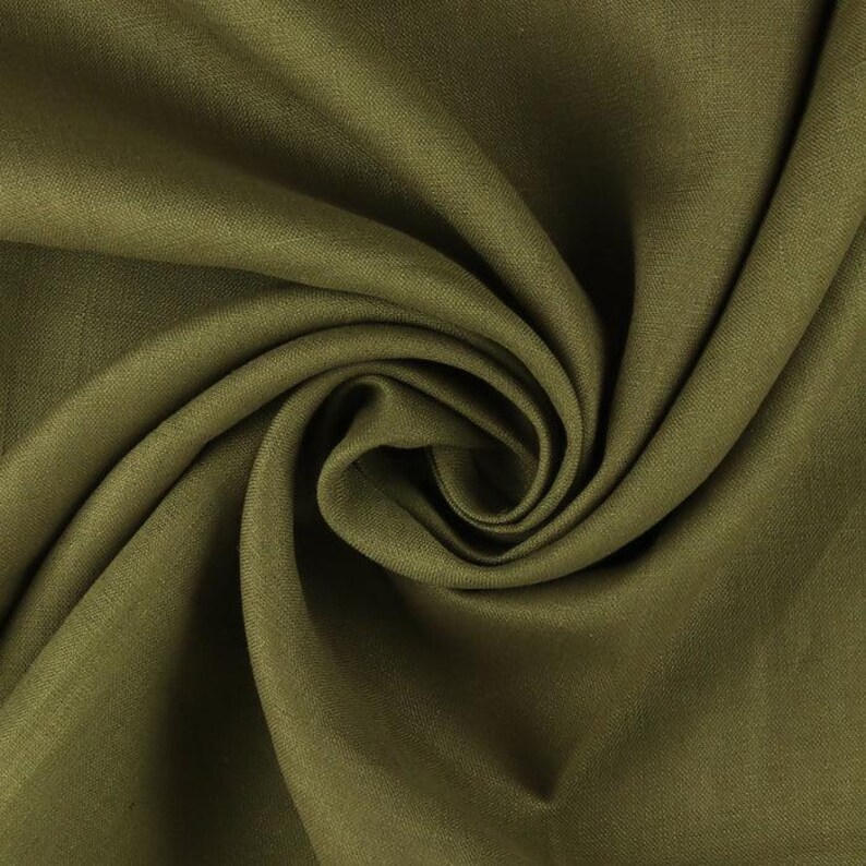 Op de afbeelding: Close-up van olijfgroene stof met een wervelend patroon. De stof heeft een gladde textuur en een lichte glans, met plooien en schaduwen die diepte cre&euml;ren. De kleur is een gedempte, aardse tint.