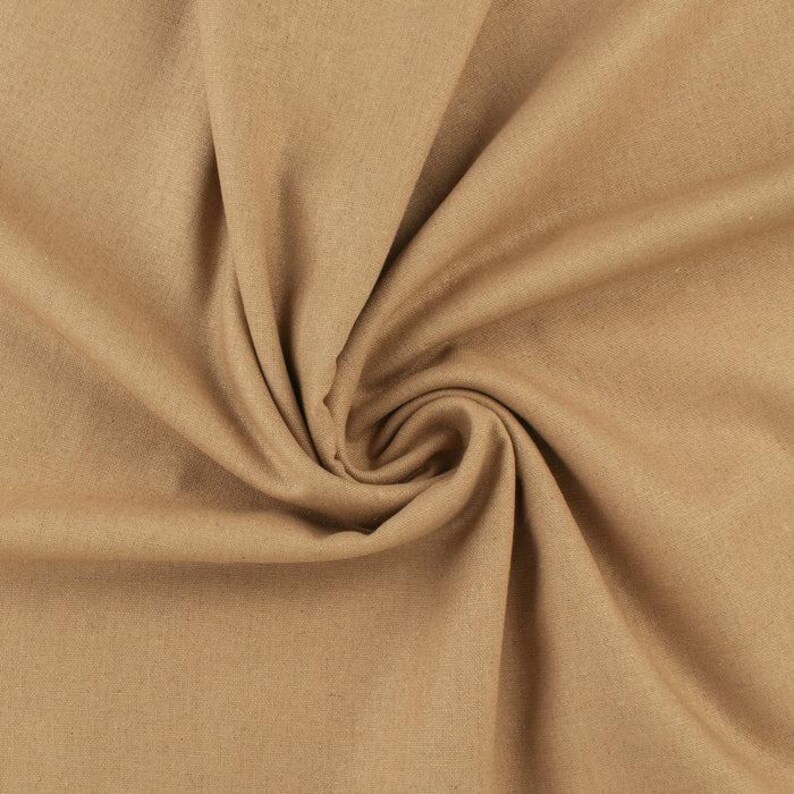 Op de afbeelding: Close-up van een bruin textiel met een wervelend patroon. De stof heeft een zachte, matte uitstraling en een subtiele textuur. De plooien en rondingen cre&euml;ren schaduwen en highlights, waardoor diepte aan de afbeelding wordt toegevoegd. De stof lijkt een materiaal van gemiddeld gewicht te zijn.