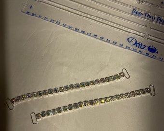 May include: Two silver bra strap extenders with clear iridescent rhinestones. The extenders are about 6 inches long.
