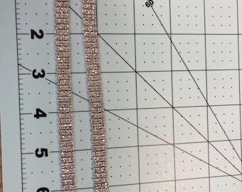 May include: Two silver bra straps with clear rhinestone embellishments. The straps are approximately 7 inches long and have a hook and eye closure.
