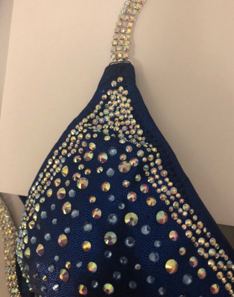 May include: A navy blue bikini top with iridescent rhinestones in a geometric pattern.