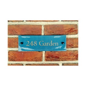 以下が含まれることがあります： 金色の文字で「248 Garden」と書かれた青いセラミック製の家の番号札。レンガの壁に取り付けられています。
