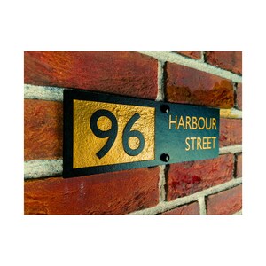 May include: Black and gold house number sign with the number 96 and the street name Harbour Street.