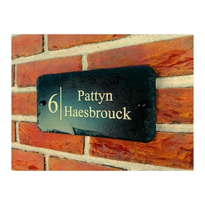 Peut inclure: Plaque de numéro de maison en ardoise noire avec inscription dorée. La plaque indique "6 Pattyn Haesbrouck".