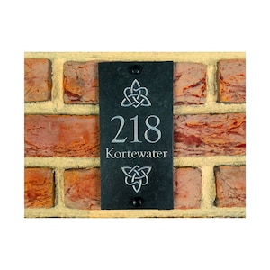 Puede incluir: Placa de número de casa de pizarra negra con un diseño de nudo celta, el número 218 y el nombre Kortewater.