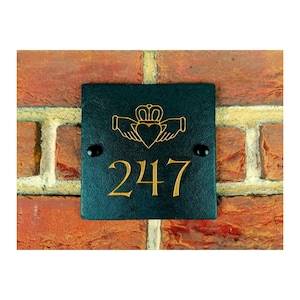 May include: Black slate house number sign with gold lettering. The number 247 is displayed on the sign. A Celtic knot design with a heart and crown is above the number.