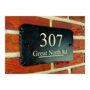 May include: Black slate house number sign with gold lettering. The number 307 and the street name Great North Rd are engraved on the sign.