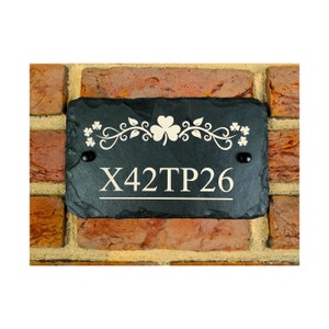 May include: Black slate house number sign with a white shamrock design and the text "X42TP26".