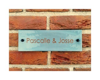 May include: A light blue rectangular sign with black screws and the text "Pascalle & Josse" in copper lettering.
