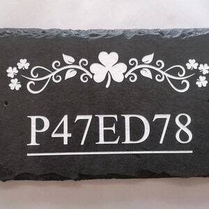 May include: Black slate house number sign with white lettering and a shamrock design. The house number is P47ED78.