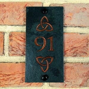 Puede incluir: Placa de número de casa de pizarra negra con diseños de nudos celtas de color cobre y el número 91.