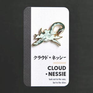 May include: Gold-colored enamel pin featuring a green and blue illustration of a mythical sea serpent emerging from clouds. The pin has the text "Cloud Nessie" and the phrase "look not to the seas, but to the skies".