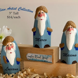 May include: Three wooden figurines of bearded men wearing blue coats and brown hats. The figurines are 3 inches tall and are named Luciano, Marco, and Maximo. The text "Italian Artist Collection" and "Country Wood Spirit" is also visible in the image.