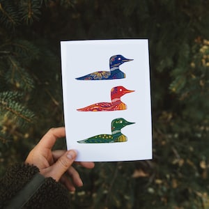 May include: A white card with three colorful loon illustrations. The loons are in a row, with the top loon blue, the middle loon red, and the bottom loon green. Each loon has a detailed pattern.