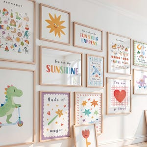 Puede incluir: Una colección de láminas artísticas enmarcadas con temática infantil, con ilustraciones y texto coloridos. Las láminas incluyen imágenes de un sol, un dinosaurio, un corazón y las frases "You are my Sunshine" y "Play All Day."