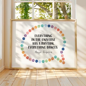 May include: A framed print with the quote "EVERYTHING IN THE UNIVERSE HAS A RHYTHM, EVERYTHING DANCES - Maya Angelou." The quote is inside a speech bubble shape, outlined with colorful circles. The frame is gold.