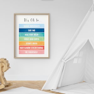 Op de afbeelding: Een ingelijst afdruk met een regenboogkleurige achtergrond en de tekst "It's OK to..." gevolgd door een lijst met zinnen: "Make Mistakes", "Say No", "Ask for Help", "Have Bad Days", "Start Over", "Not Know Everything" en "Be Yourself".