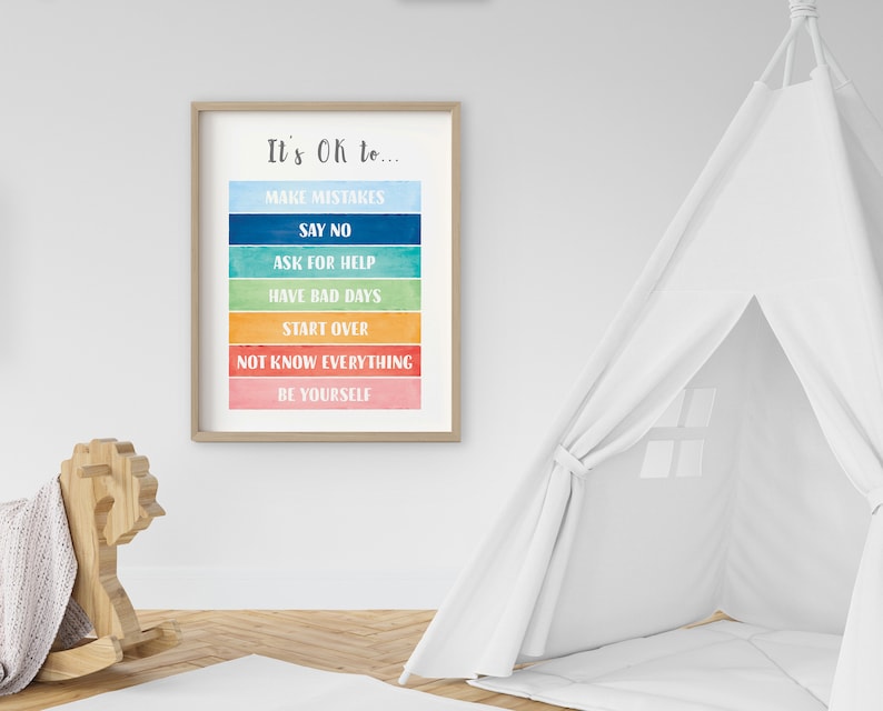 Op de afbeelding: Een ingelijst afdruk met een regenboogkleurige achtergrond en de tekst "It's OK to..." gevolgd door een lijst met zinnen: "Make Mistakes", "Say No", "Ask for Help", "Have Bad Days", "Start Over", "Not Know Everything" en "Be Yourself".