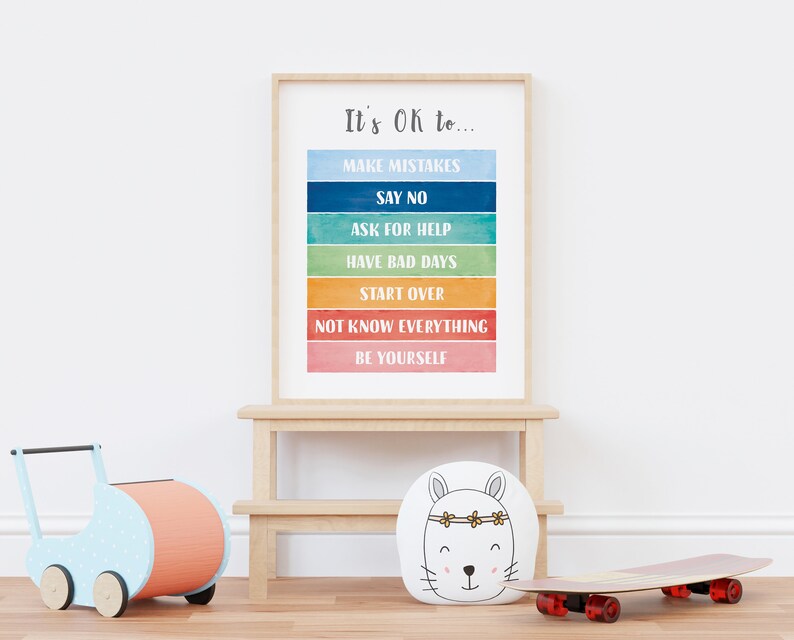 Op de afbeelding: Een ingelijst print met een regenboogachtergrond en de tekst "It's Ok to..." gevolgd door een lijst met zinnen, waaronder "Make Mistakes", "Say No", "Ask for Help", "Have Bad Days", "Start Over", "Not Know Everything" en "Be Yourself".