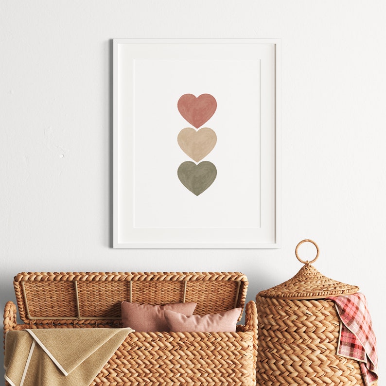 May include: A framed print with three watercolor hearts in shades of pink, beige, and green. The hearts are arranged vertically in a row.