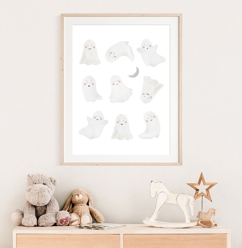 Puede incluir: Una impresi&oacute;n enmarcada de una ilustraci&oacute;n de acuarela con 10 fantasmas blancos con mejillas rosadas. Los fantasmas est&aacute;n en varias poses, incluyendo volar, dormir y sonre&iacute;r. Una luna creciente est&aacute; en la esquina superior derecha de la impresi&oacute;n.