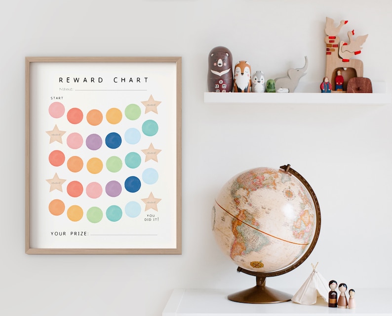 May include: A colorful reward chart with a white background and a wooden frame. The chart has a title that says "Reward Chart" and has a space for a name. The chart has 25 circles in a grid pattern, with each circle filled with a different color. There are four stars at the top of the chart and one at the bottom. The text "You Did It!" is below the bottom star. The text "Your Prize" is at the bottom of the chart.