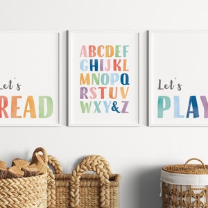 May include: Three framed prints with colorful watercolor text. The left print says "Let's READ" in rainbow colors. The middle print has the alphabet in rainbow colors. The right print says "Let's PLAY" in blue, green, and purple.