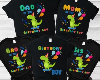 May include: Set of five black t-shirts with a green dinosaur graphic and text that reads "Dad of the Birthday Boy", "Mum of the Birthday Boy", "Bro of the Birthday Boy", "Sis of the Birthday Boy", and "Birthday Boy".