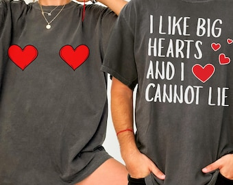 May include: Two dark gray t-shirts. One has two red hearts, the other says "I LIKE BIG HEARTS AND I CANNOT LIE" in white text with red heart accents. Both shirts are short-sleeved.