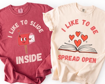 May include: Two t-shirts with Valentine's Day graphics. One is red with a mailbox graphic and the text "I like to slide inside". The other is cream-colored with hearts and the text "I like to be spread open".
