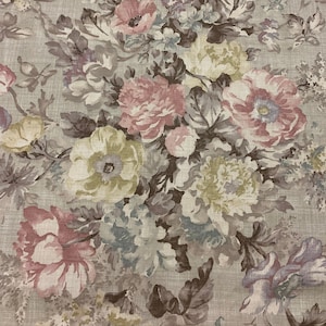 Op de afbeelding: Een beige stof met een bloemenpatroon met roze, bruine en groene bloemen. De stof heeft een subtiele linnen textuur.