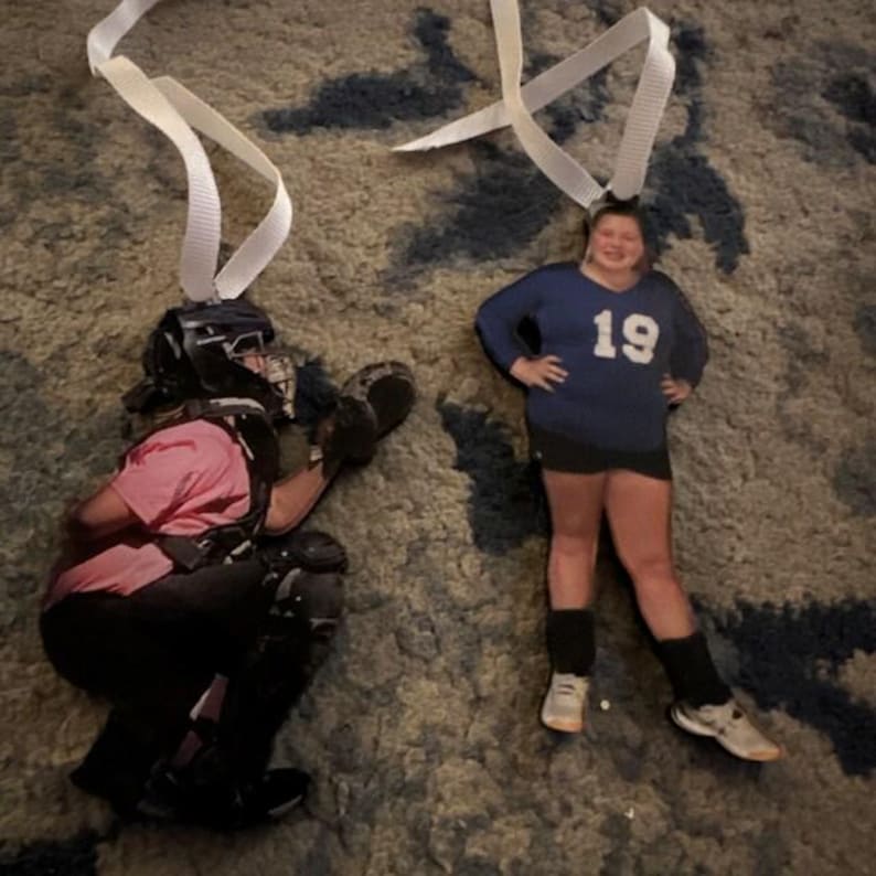 May include: Two custom photo ornaments with white ribbon hangers. One ornament shows a catcher in a pink shirt, black helmet, and protective gear. The other ornament shows a player in a dark blue long-sleeve shirt with the number 19, black shorts, and white sneakers.