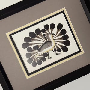 Puede incluir: Obra de arte enmarcada que representa un pájaro estilizado con cola en forma de abanico. El pájaro está en negro, gris y crema, sobre un fondo blanco. La obra de arte está enmarcada con bordes crema y gris y está encerrada en un marco negro.