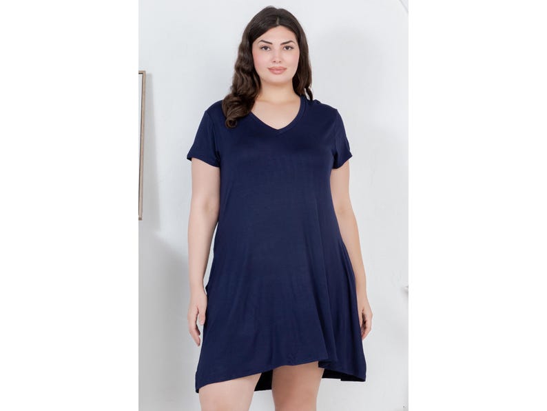 Puede incluir: Vestido azul marino de manga corta con cuello en V. El vestido tiene un dobladillo asim&eacute;trico y fluido. La modelo lleva el vestido en un estudio con fondo blanco.