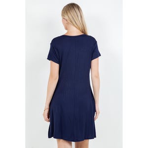 Puede incluir: Vestido azul marino de manga corta con cuello redondo. El vestido tiene un dise&ntilde;o sencillo y fluido y llega hasta la rodilla. La modelo est&aacute; de espaldas.