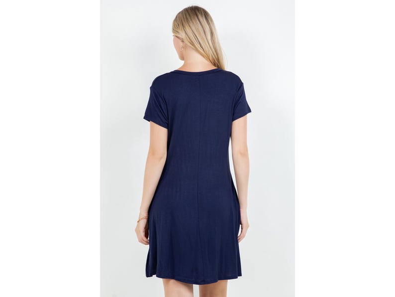 Puede incluir: Vestido azul marino de manga corta con cuello redondo. El vestido tiene un dise&ntilde;o sencillo y fluido y llega hasta la rodilla. La modelo est&aacute; de espaldas.