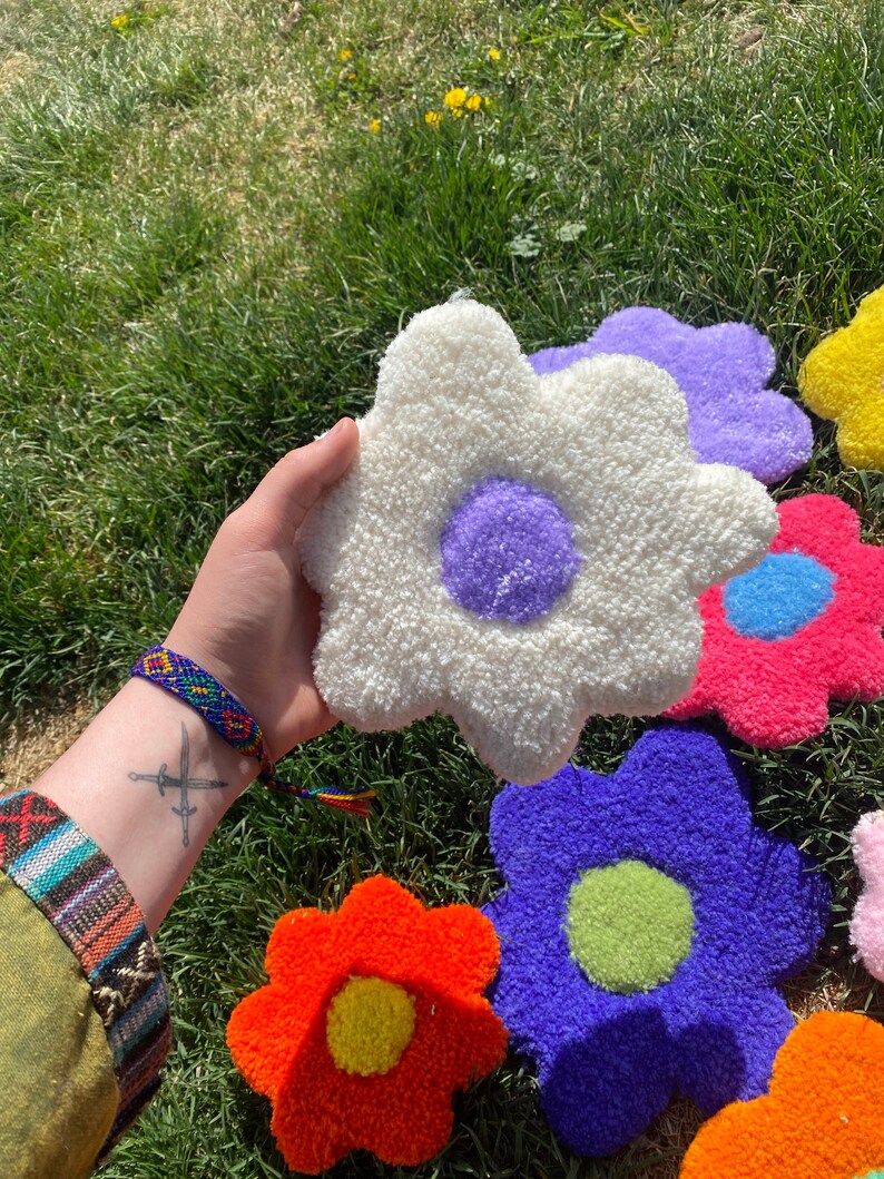 May include: A collection of colorful, fluffy, daisy-shaped rugs with different colored centers. The rugs are made of a soft, fuzzy material and are perfect for adding a touch of whimsy to any room.