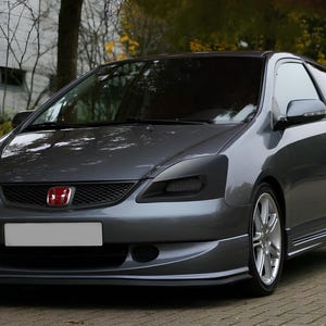 May include: A gray Honda Civic with blacked-out headlights and a red Honda emblem on the front grille.