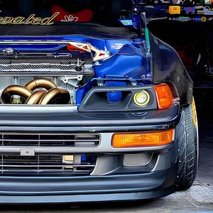 May include: A blue Honda Civic with a custom carbon fibre bonnet and aftermarket headlights. The car has a custom exhaust system and a Bride racing seat. The car is sitting on a concrete surface.