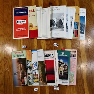 May include: A collection of vintage California road maps, including maps from Mobil, Shell, Touraide, and AAA. The maps are in various sizes and colors, and some feature vintage illustrations.