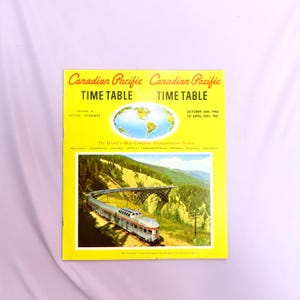 May include: A yellow and red cover of a Canadian Pacific Time Table booklet. The cover features a world map and a photo of a train crossing a bridge in a mountainous landscape. The text on the cover reads "Canadian Pacific Time Table" and "October 30th, 1960 to April 29th, 1961".