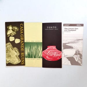 May include: Four vintage travel brochures. The brochures feature images and text for Casa Grande Ruins, Organ Pipe Cactus, Tonto National Monument, and Glen Canyon Dam and Powerplant. The brochures are in various colors, including brown, black, and beige.