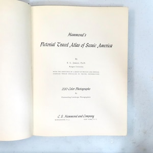 May include: Open book with the title "Hammond's Pictorial Travel Atlas of Scenic America." The page features text detailing the author, E. L. Jordan, Ph.D., and the inclusion of 220 color photographs. The publisher is C. S. Hammond and Company.