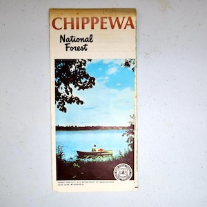 May include: A vintage map of the Chippewa National Forest in Cass Lake, Minnesota. The map features a scenic image of a lake with a canoe and a person paddling. The text "Chippewa National Forest" is printed in bold at the top of the map.