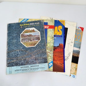 Puede incluir: Una colección de atlas de carreteras y guías de viaje vintage. Los atlas son de varios colores, incluyendo azul, rojo y marrón. Las portadas presentan imágenes de paisajes y ciudades. El texto en las portadas incluye "Rand McNally Road Atlas", "National Missions", "Texas" y "Of Mexico".