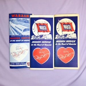 May include: Three vintage Wabash Railroad timetables with blue covers and red hearts featuring a map of the railroad's routes. The covers feature the text "Follow the Flag" and the Wabash logo.