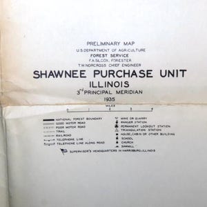 May include: A black and white map of the Shawnee Purchase Unit in Illinois, 3rd Principal Meridian, 1935. The map shows national forest boundaries, roads, trails, railroads, telephone lines, and other features. It also includes a legend explaining the symbols used on the map.