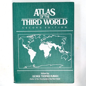May include: A green book titled "Atlas of the Third World, Second Edition." The cover features a world map outline in white and the text "Edited by George Thomas Kurian, Author of the Encyclopedia of the Third World."