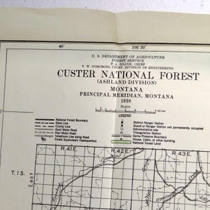May include: A vintage map of Custer National Forest in Montana, dated 1938. The map, from the U.S. Department of Agriculture, features a legend with symbols for ranger stations, roads, and boundaries. The scale is marked in miles.